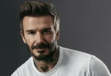 صورة ديفيد بيكهام يرتدي بدلة أنيقة وهو يبتسم أمام خلفية بسيطة