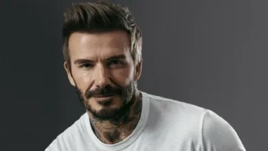 صورة ديفيد بيكهام يرتدي بدلة أنيقة وهو يبتسم أمام خلفية بسيطة